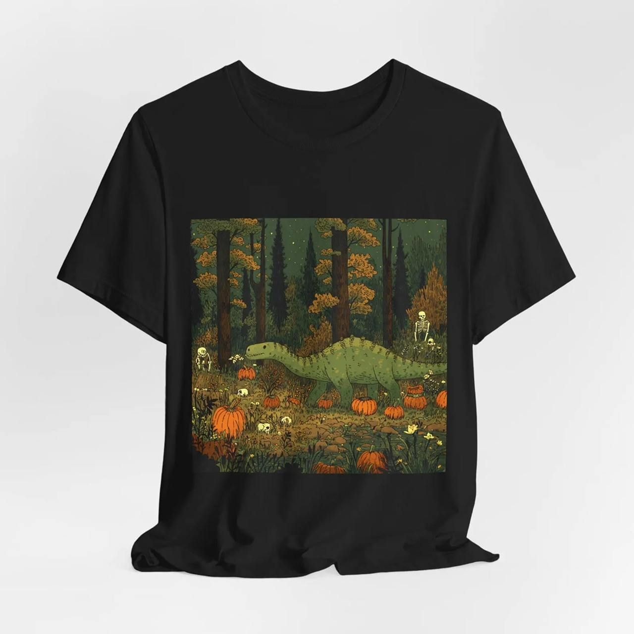A black Halloween t-shirt with an illustrated scene of a dinosaur in a forest, surrounded by pumpkins and small skeletons.